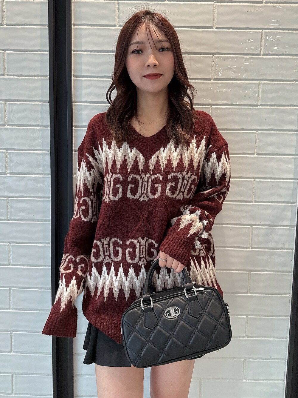 レッド系のニット/セーター、ブラック系のスカート、ブラック系のハンドバッグを着用したレディースの冬コーディネートの4枚目の写真