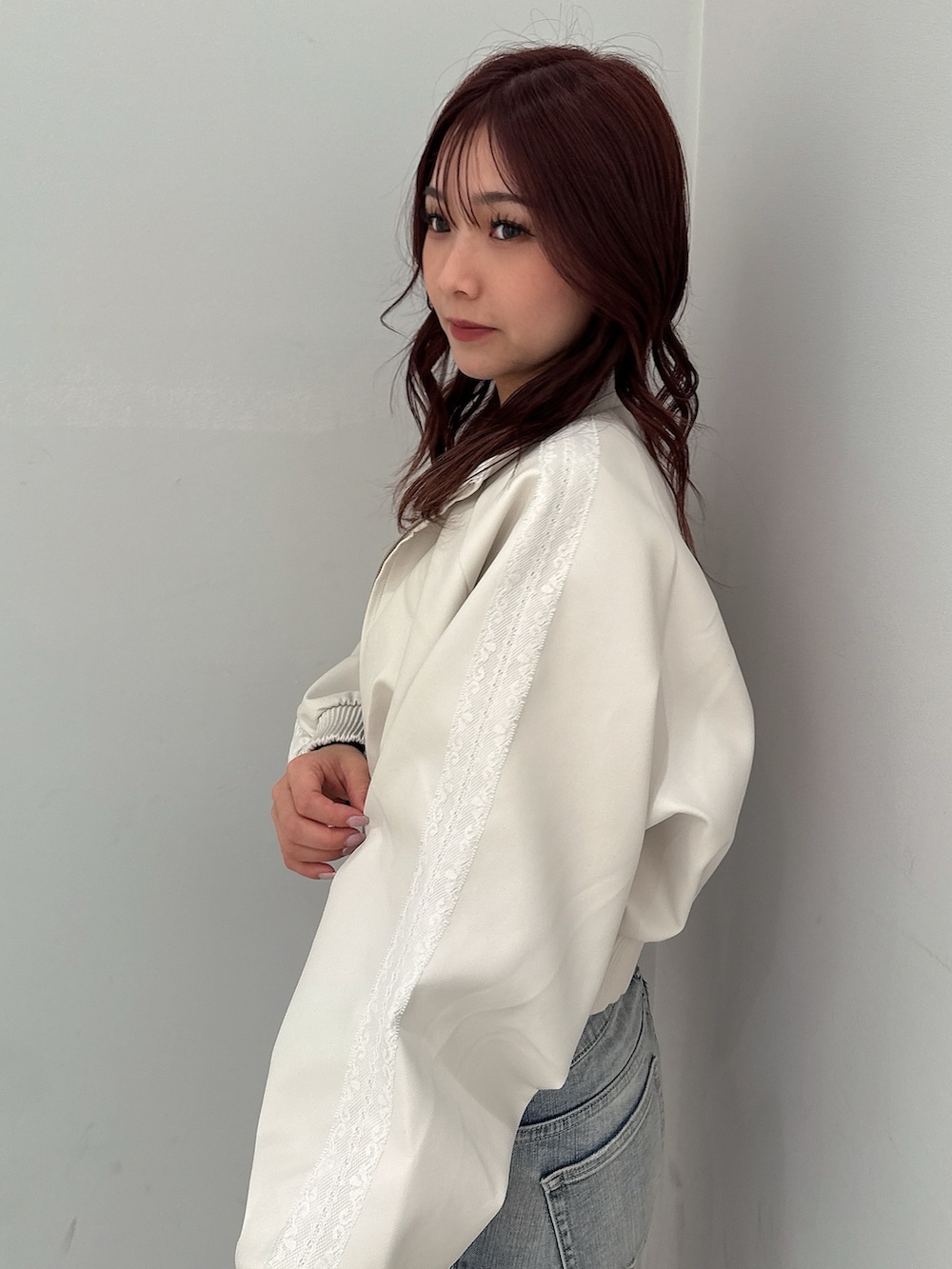 ホワイト系のブルゾン、ブラック系のニット/セーター、ブルー系のデニムパンツを着用したレディースの冬コーディネートの5枚目の写真