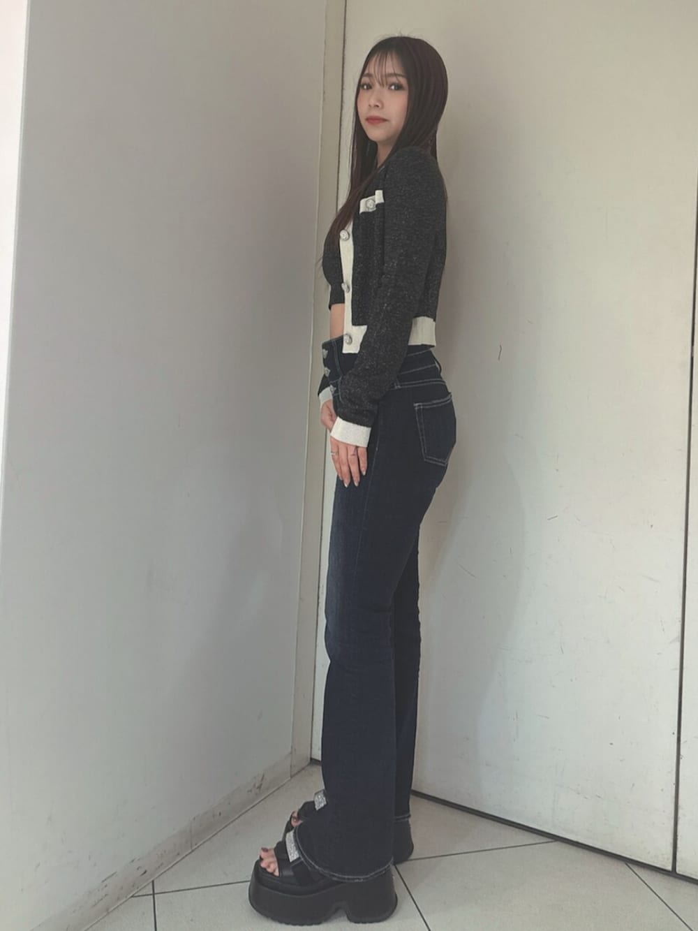 ブルー系のデニムパンツ、ブラック系のサンダル、ブラック系のニット/セーターを着用したレディースの春コーディネートの2枚目の写真