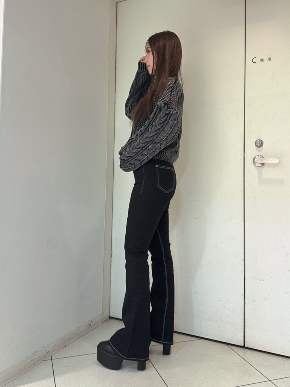 ブラック系のデニムパンツ、ブラック系のブーツ、ブラック系のニット/セーターを着用したレディースの夏コーディネートの2枚目の写真