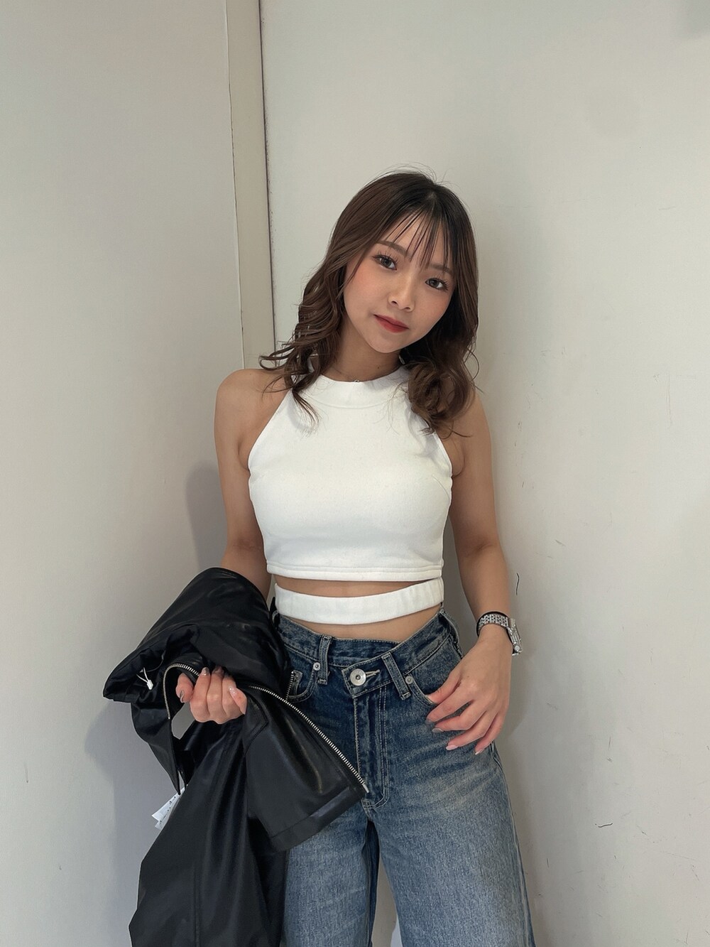 ブルー系のデニムパンツ、ブラック系のライダースジャケット、ホワイト系のタンクトップを着用したレディースの冬コーディネートの5枚目の写真