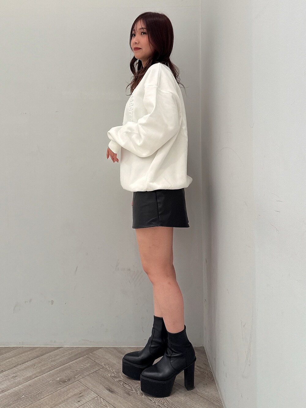 ブラック系のスカート、ブラック系のブーツ、ホワイト系のスウェットを着用したレディースの冬コーディネートの2枚目の写真