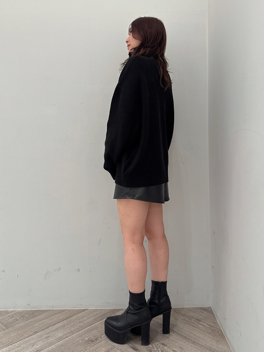 ブラック系のスカート、ブラック系のニット/セーター、ブラック系のブーツを着用したレディースの冬コーディネートの2枚目の写真