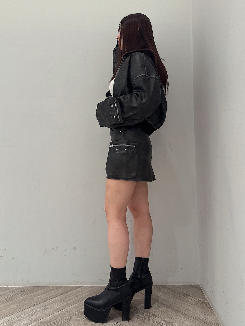 ブラック系のブーツ、ホワイト系のニット/セーター、ブラック系のスカートを着用したレディースの秋コーディネートの2枚目の写真