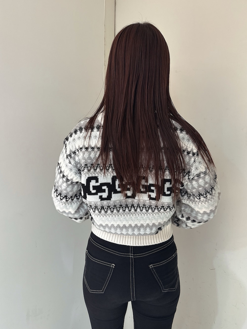 ブラック系のデニムパンツ、ブラック系のブーツ、ホワイト系のニット/セーターを着用したレディースの秋コーディネートの6枚目の写真