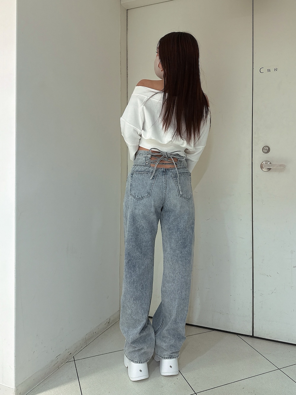 ホワイト系のスウェット、ブルー系のデニムパンツ、ホワイト系のサンダルを着用したレディースの冬コーディネートの3枚目の写真