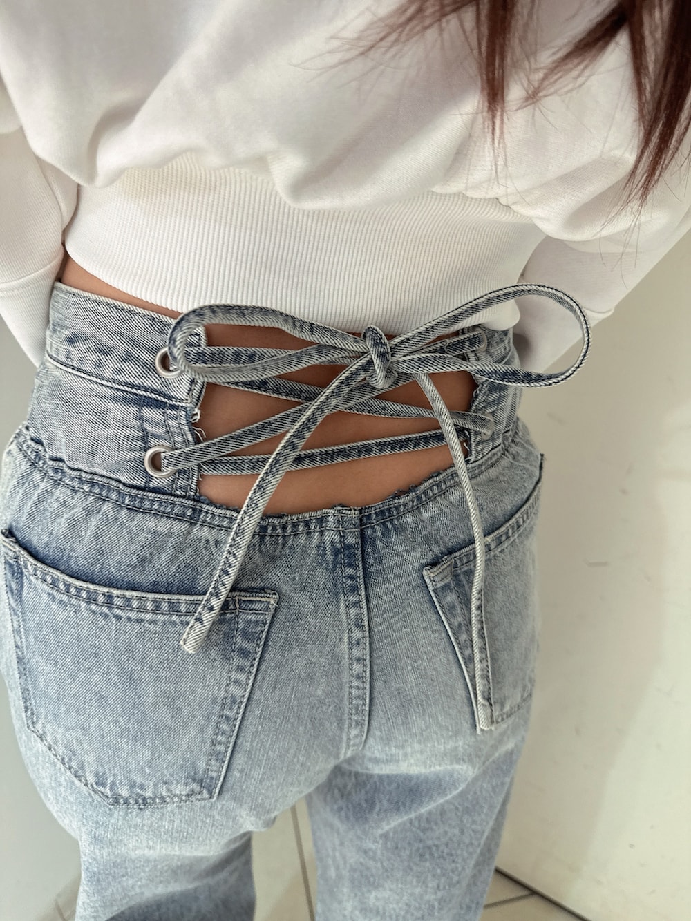 ホワイト系のスウェット、ブルー系のデニムパンツ、ホワイト系のサンダルを着用したレディースの冬コーディネートの8枚目の写真