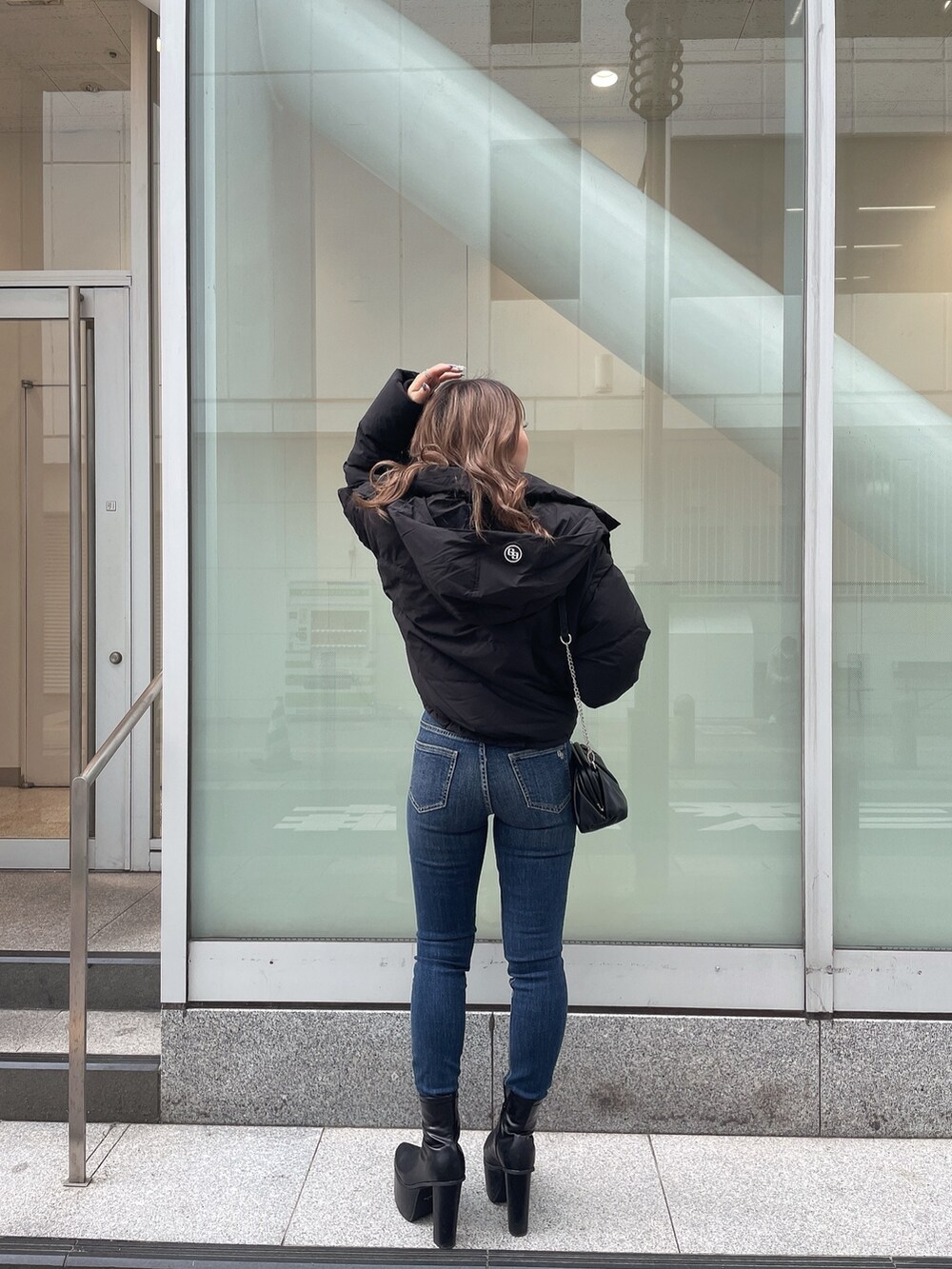 ブラック系のダウンジャケット/コート、ベージュ系のニット/セーター、ブルー系のデニムパンツを着用したレディースの秋コーディネートの3枚目の写真