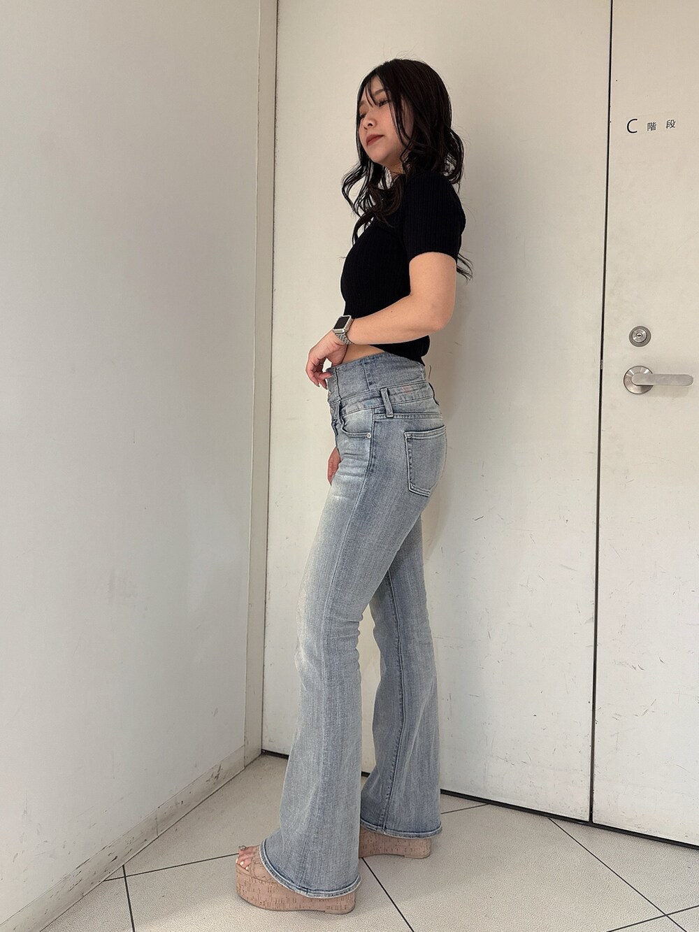 ブルー系のデニムパンツ、ブラック系のニット/セーター、ホワイト系のサンダルを着用したレディースの春コーディネートの2枚目の写真