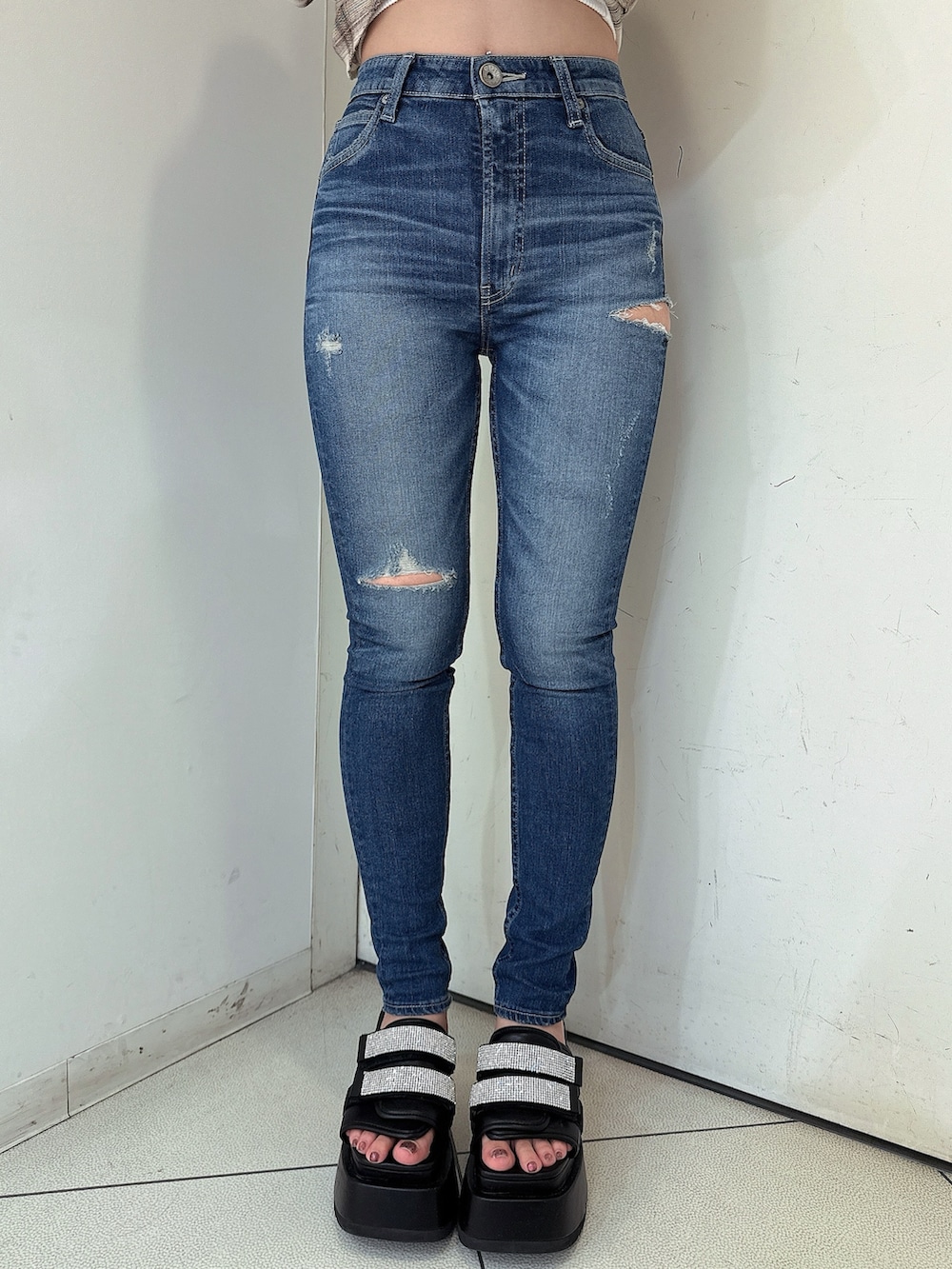 ブラック系のニット/セーター、ブルー系のデニムパンツ、ブラック系のサンダルを着用したレディースの春コーディネートの8枚目の写真