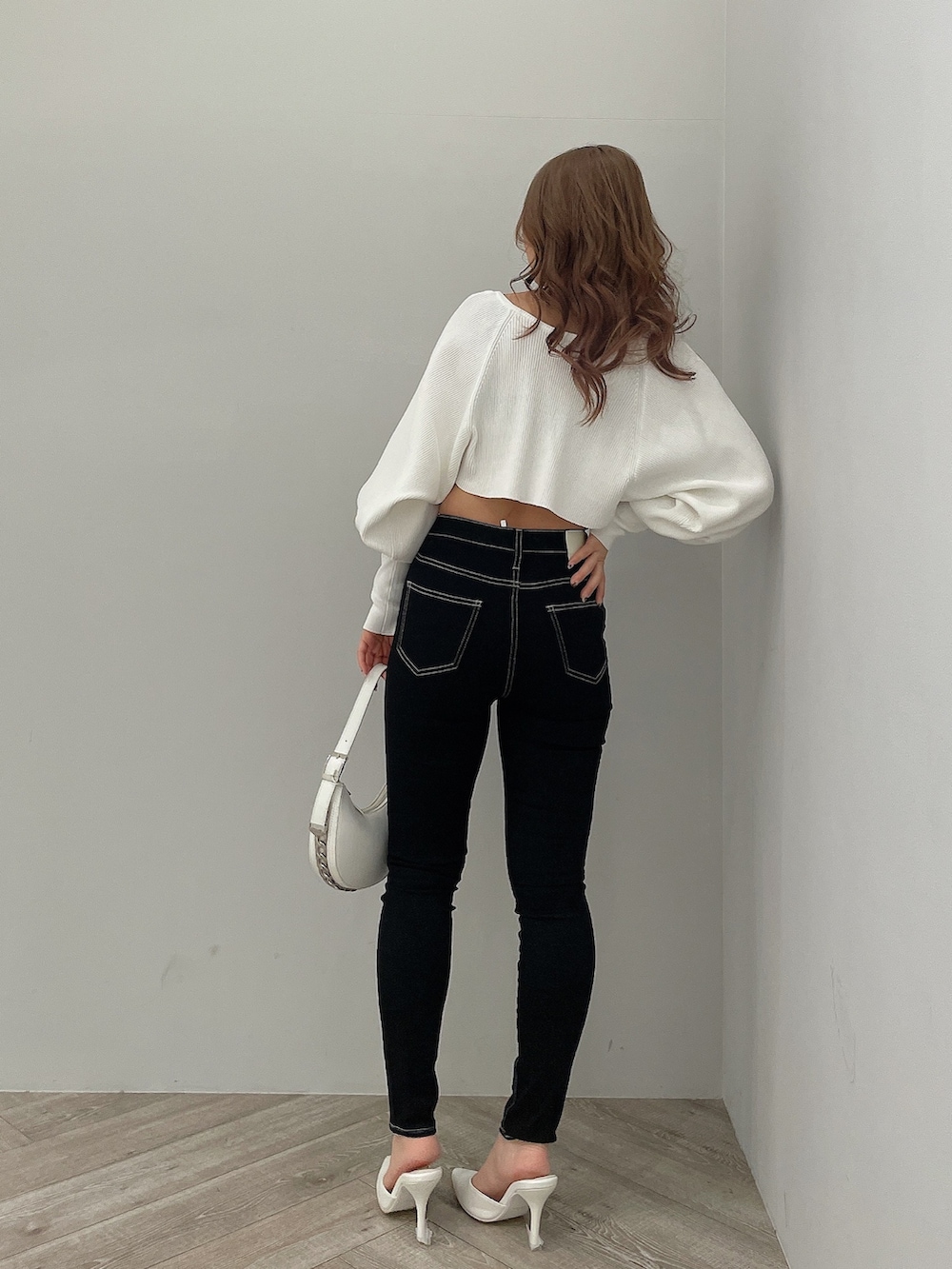 ブラック系のデニムパンツ、ブラック系のハンドバッグ、ホワイト系のパンプスを着用したレディースの春コーディネートの3枚目の写真