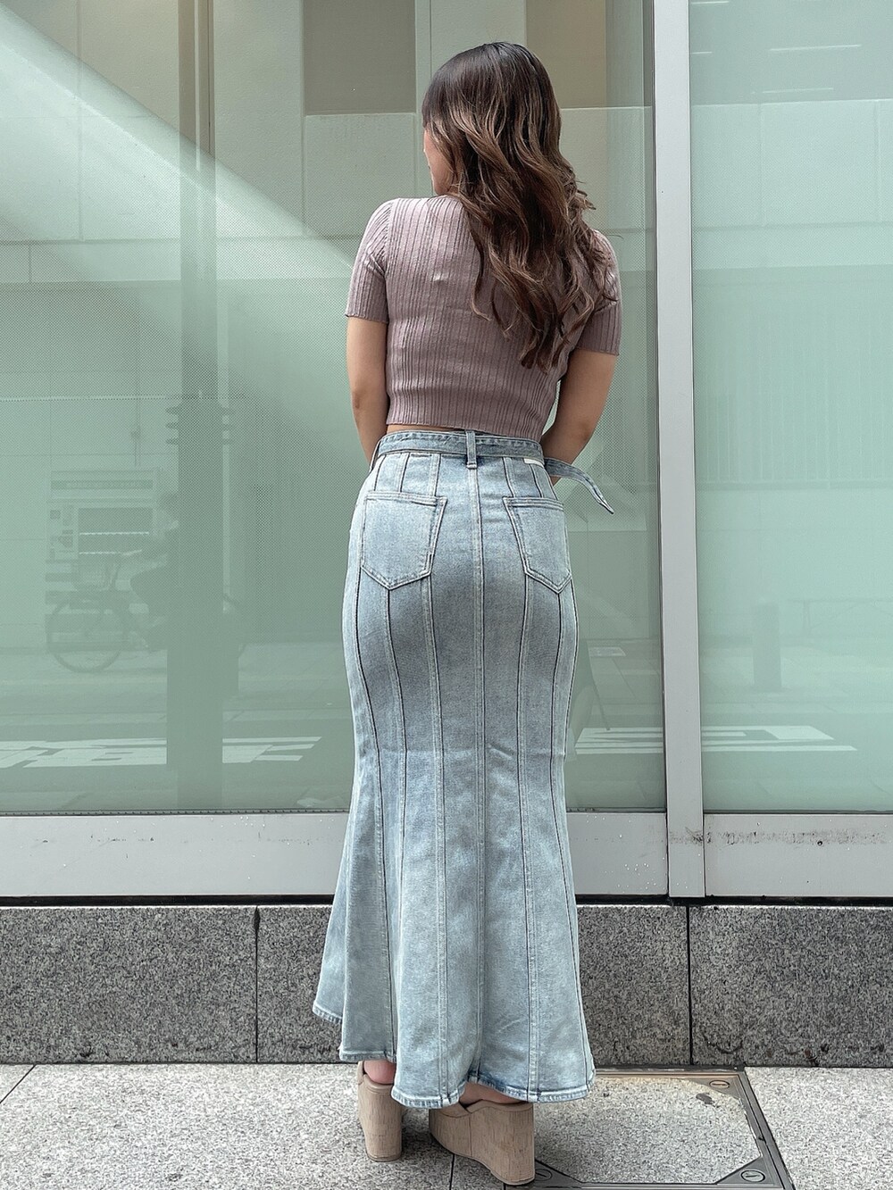 ピンク系のニット/セーター、ブルー系のデニムスカート、ホワイト系のサンダルを着用したレディースの夏コーディネートの3枚目の写真