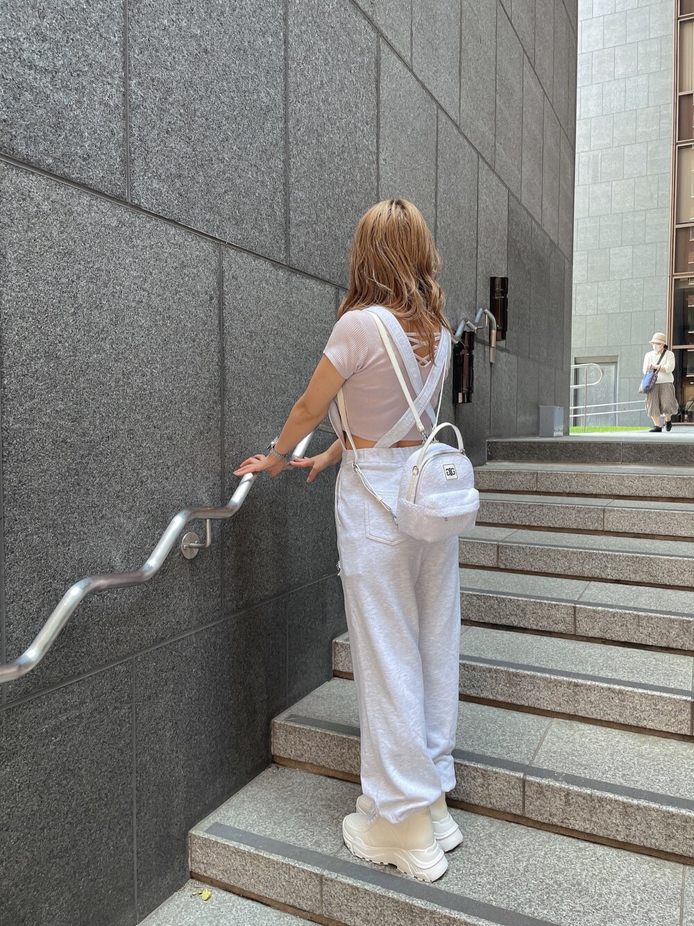 ホワイト系のスニーカー、パープル系のTシャツ/カットソー、グレー系のつなぎ/オールインワンを着用したレディースの夏コーディネートの3枚目の写真