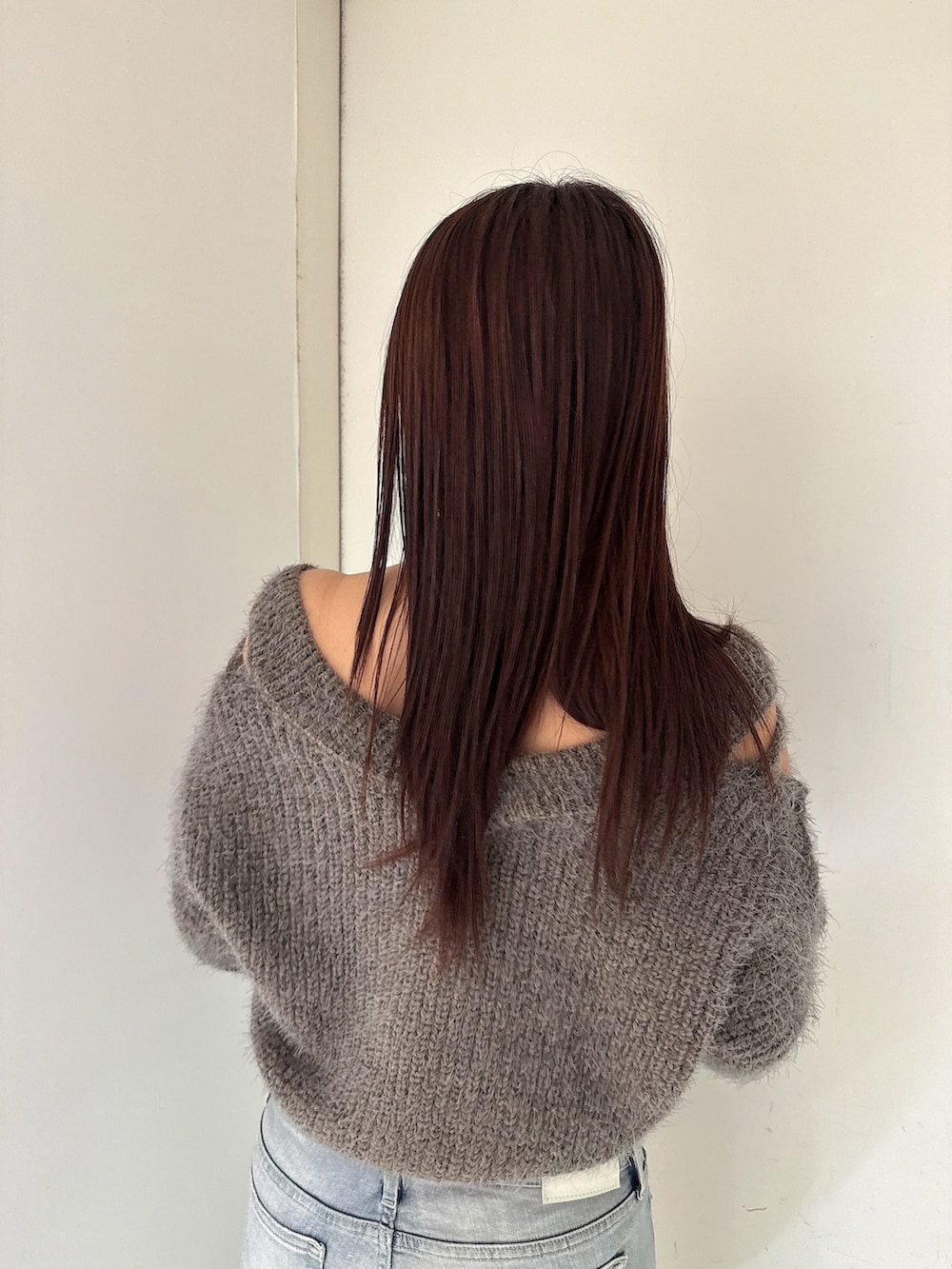 グレー系のニット/セーター、ブルー系のデニムパンツ、ブラック系のブーツを着用したレディースの秋コーディネートの6枚目の写真