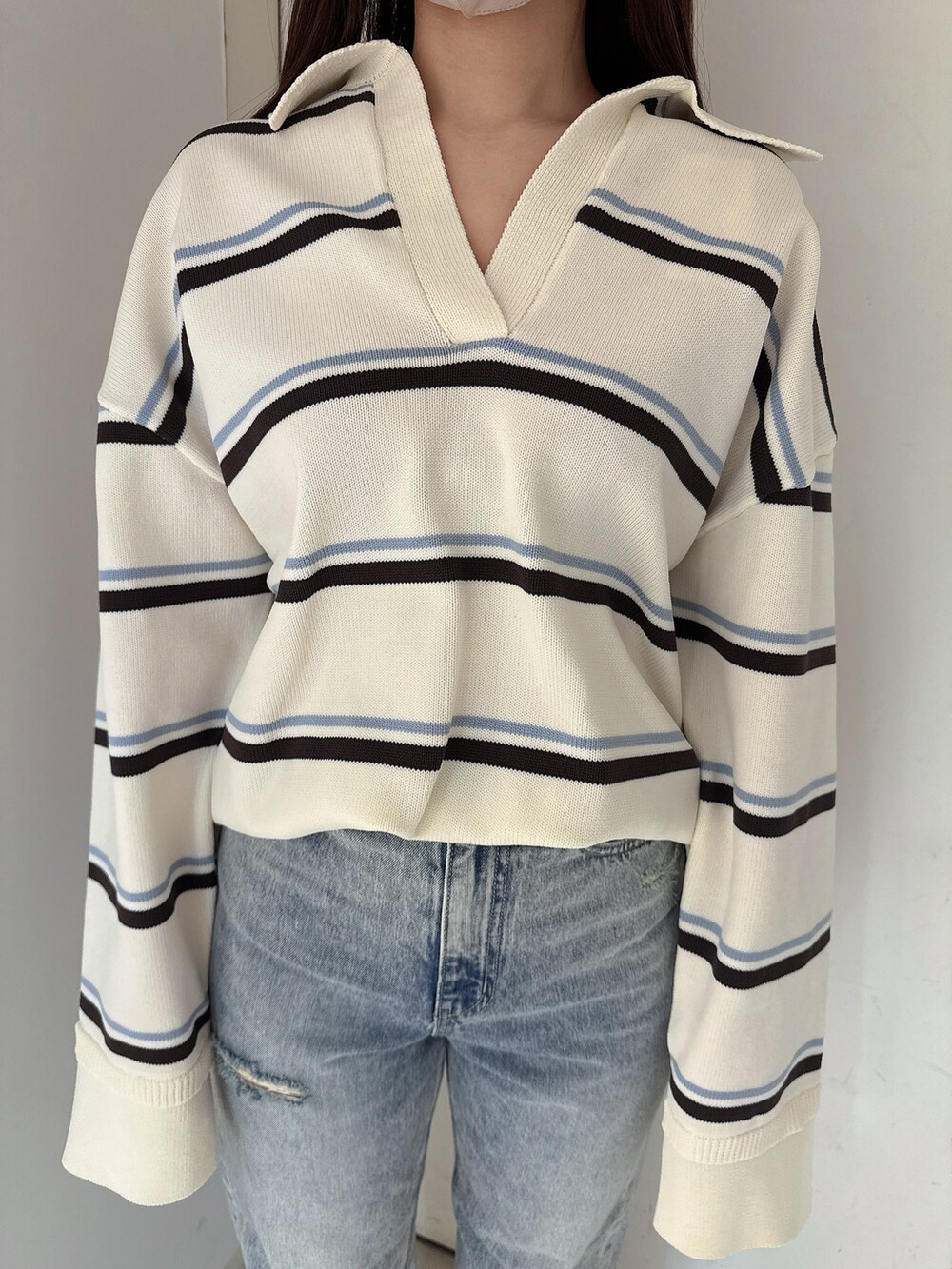 ブラック系のブーツ、ホワイト系のニット/セーター、ブルー系のデニムスカートを着用したレディースの冬コーディネートの7枚目の写真