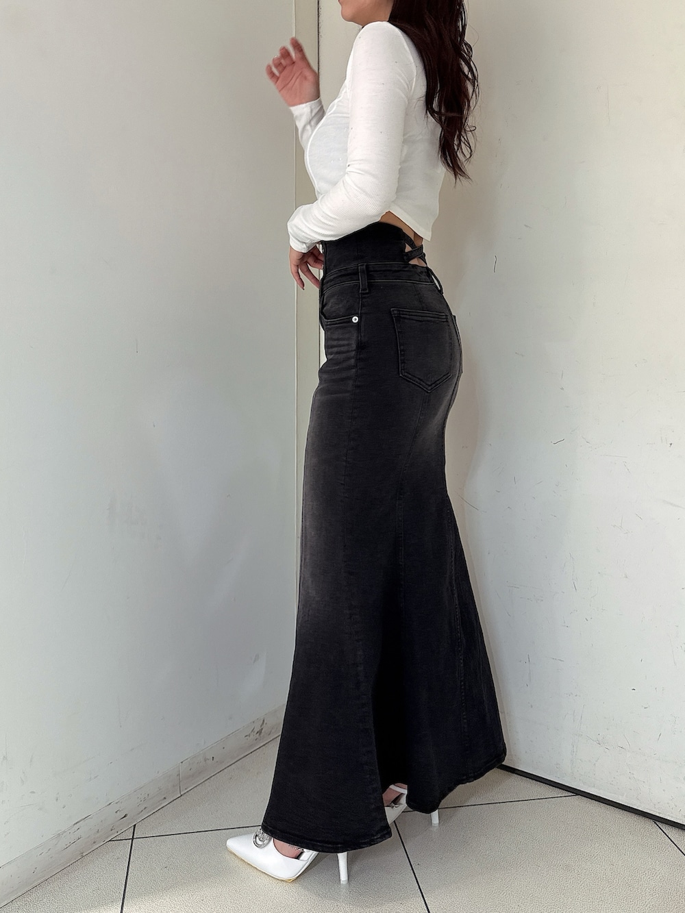 ブラック系のデニムスカート、ブラック系のTシャツ/カットソー、ホワイト系のパンプスを着用したレディースの秋コーディネートの2枚目の写真