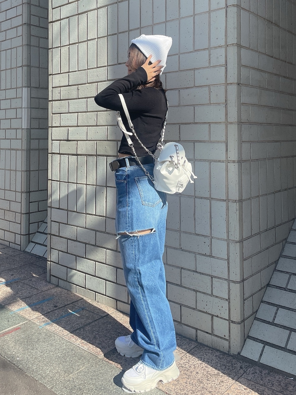 ブラック系のニット/セーター、ホワイト系のバックパック/リュック、ブルー系のデニムパンツを着用したレディースの冬コーディネートの2枚目の写真