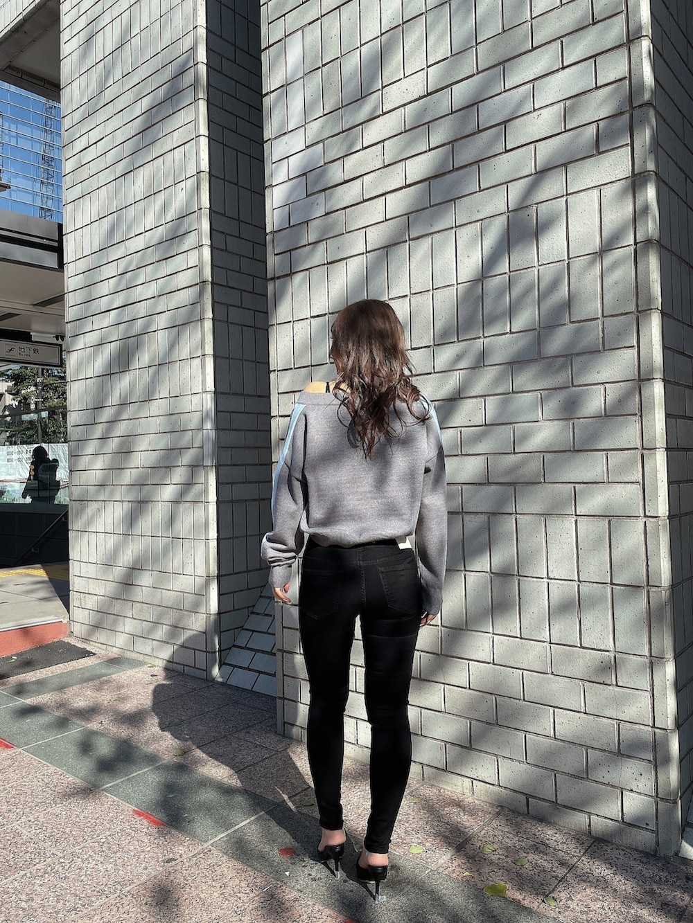 グレー系のニット/セーター、ブラック系のキャミソール、ブラック系のデニムパンツを着用したレディースの冬コーディネートの4枚目の写真