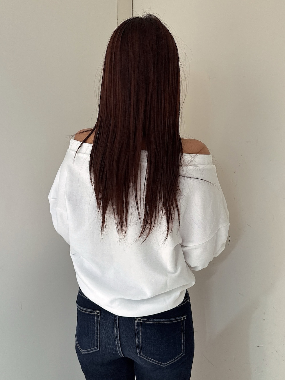 ブルー系のデニムパンツ、ブラック系のブーツ、ホワイト系のスウェットを着用したレディースの秋コーディネートの6枚目の写真