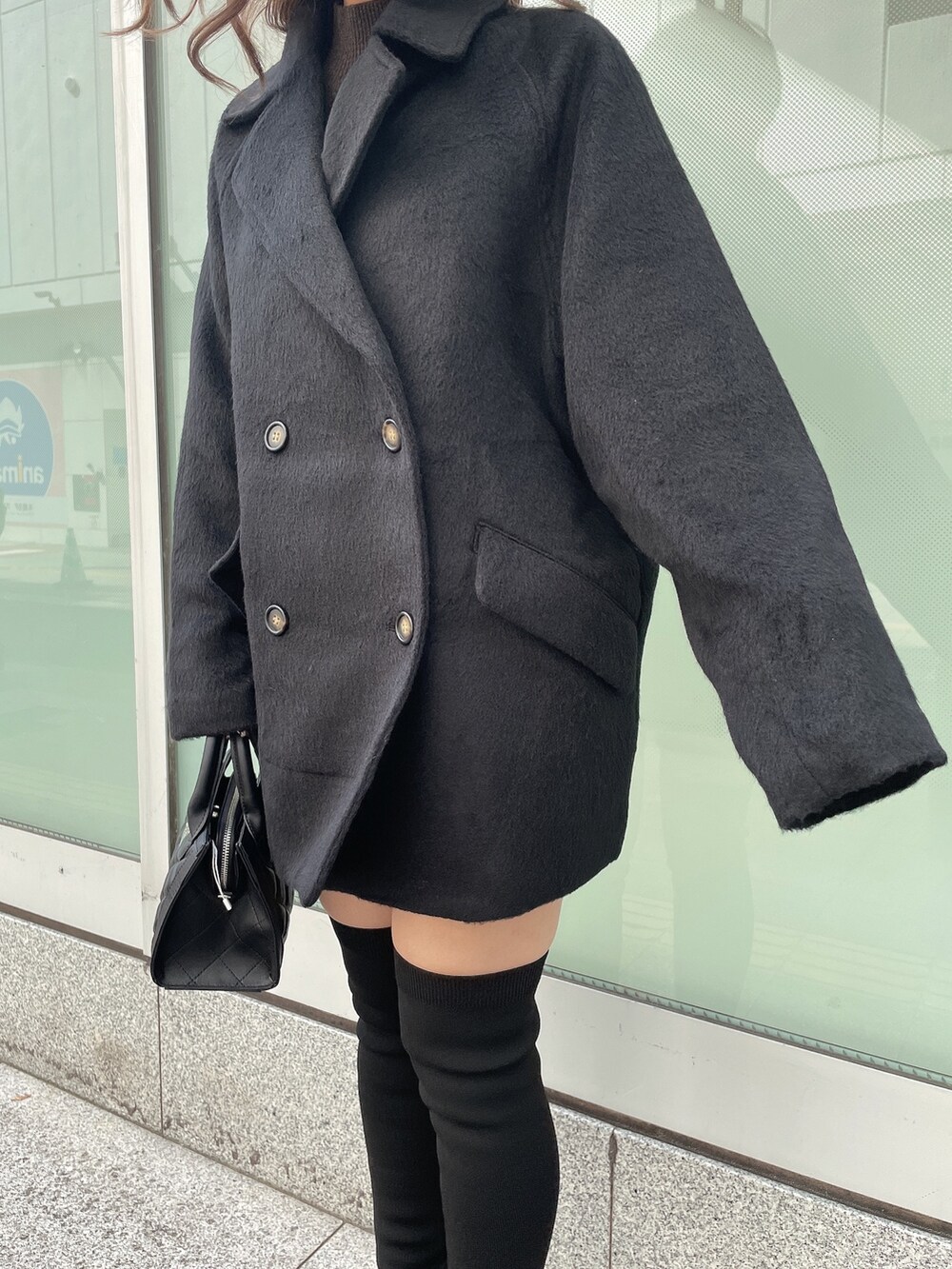 ブラック系のハンドバッグ、ブラウン系のニット/セーター、ブラック系のチェスターコートを着用したレディースの秋コーディネートの5枚目の写真
