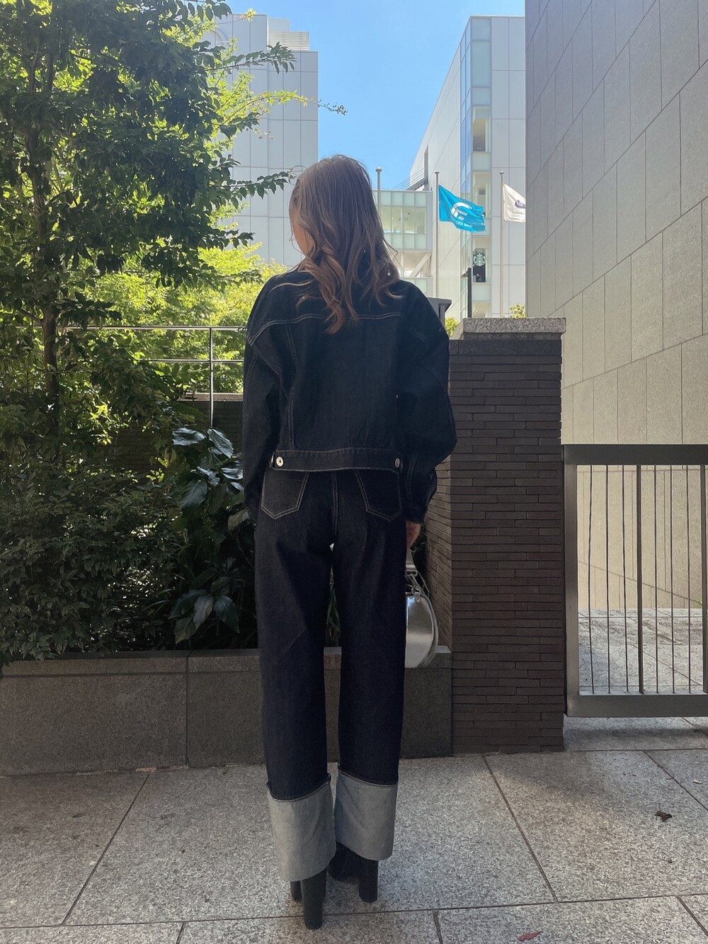 ブラック系のキャミソール、ブルー系のデニムジャケット、ブルー系のデニムパンツを着用したレディースの秋コーディネートの2枚目の写真
