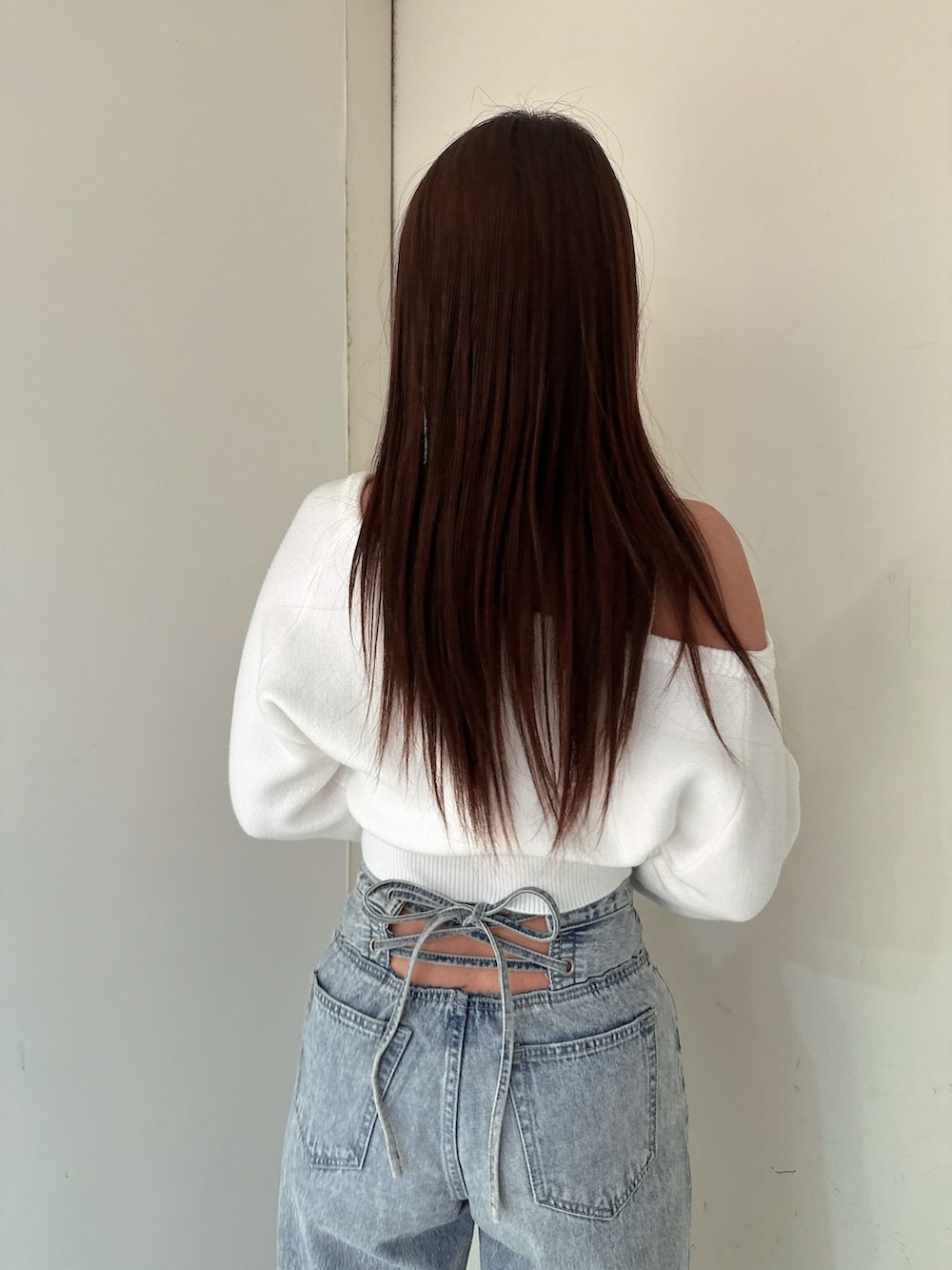 ホワイト系のニット/セーター、ブルー系のデニムパンツ、ホワイト系のパンプスを着用したレディースの冬コーディネートの6枚目の写真