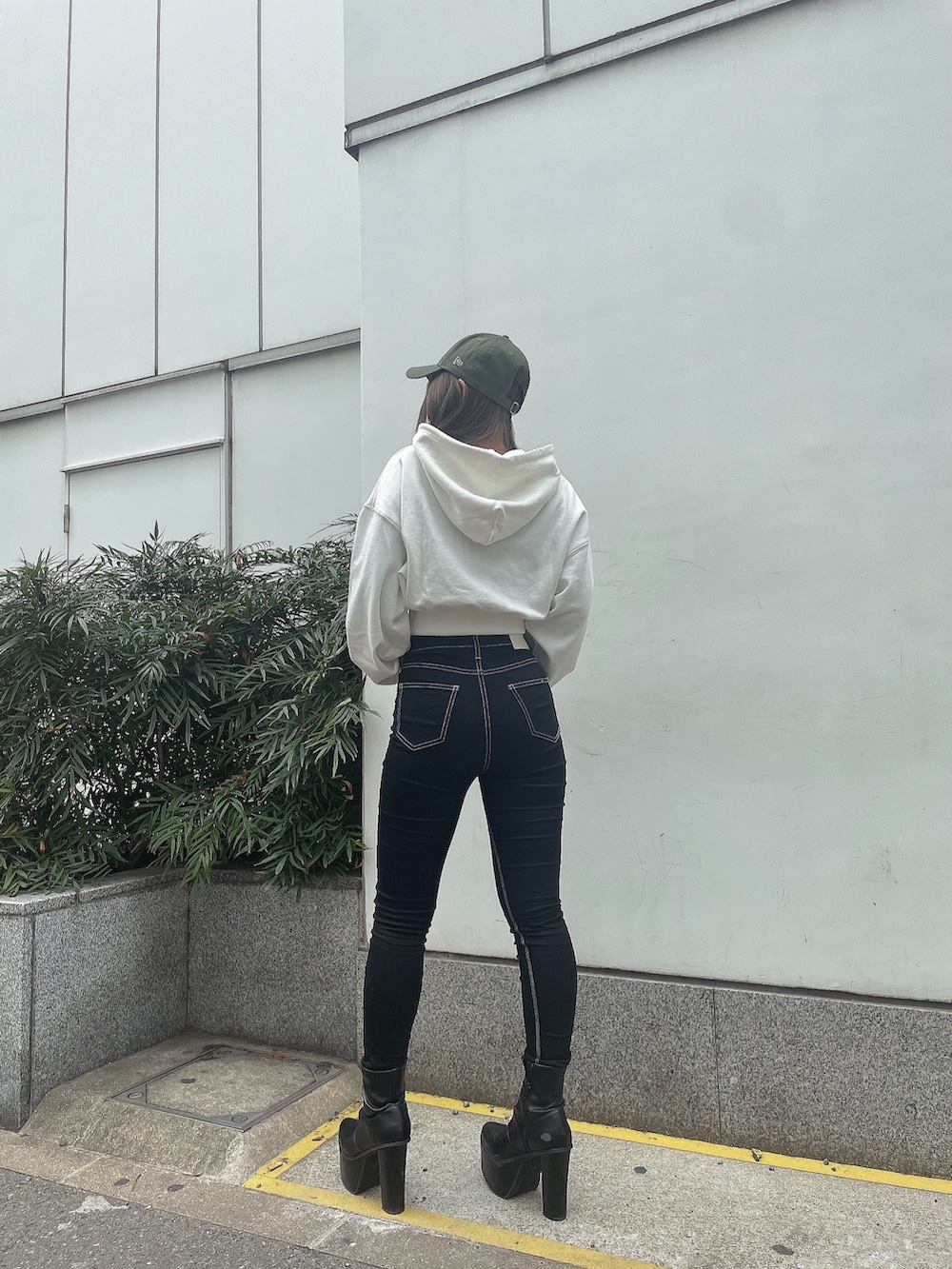 ホワイト系のパーカー、ブラック系のデニムパンツ、ブラック系のブーツを着用したレディースの冬コーディネートの2枚目の写真