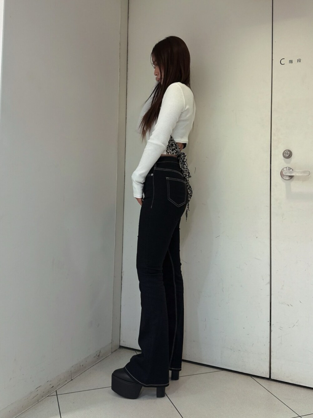 ブラック系のデニムパンツ、ブラック系のブーツ、ホワイト系のTシャツ/カットソーを着用したレディースの夏コーディネートの2枚目の写真
