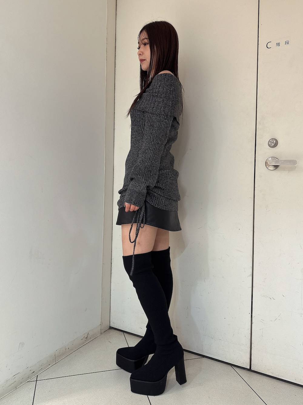 ブラック系のブーツ、ブラック系のスカート、ブラック系のチュニックを着用したレディースの秋コーディネートの2枚目の写真