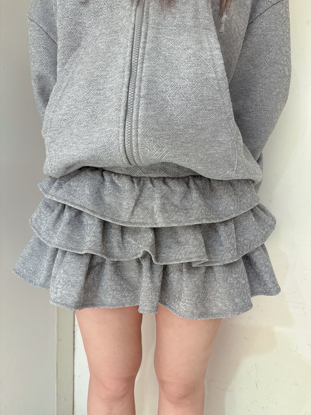 グレー系のスカート、グレー系のパーカー、ブラック系のブーツを着用したレディースの冬コーディネートの8枚目の写真