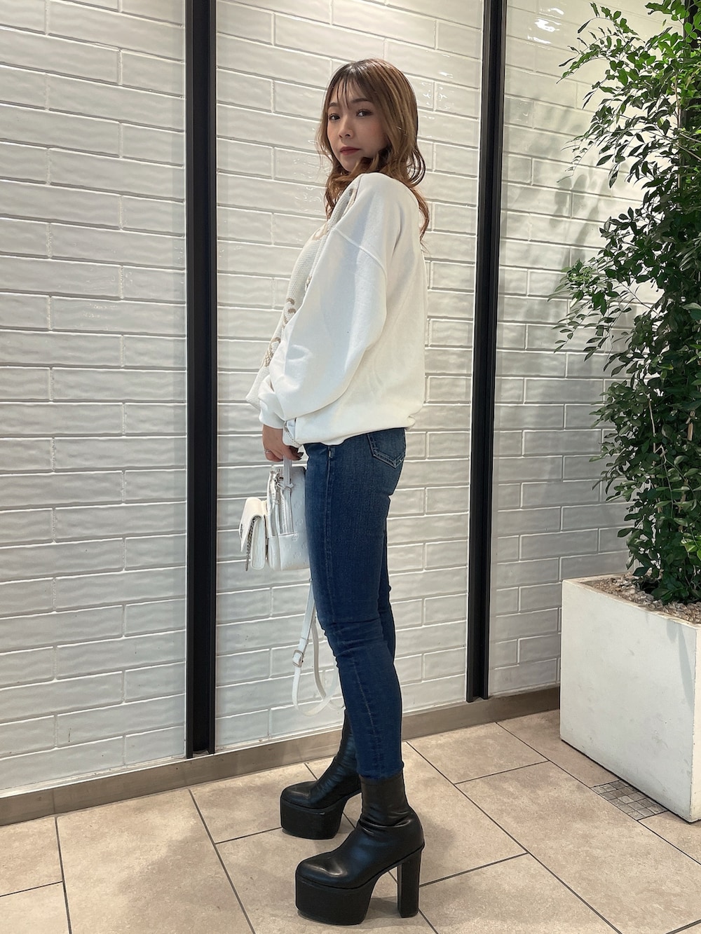 ホワイト系のTシャツ/カットソー、ホワイト系のバックパック/リュック、ブルー系のデニムパンツを着用したレディースの冬コーディネートの2枚目の写真