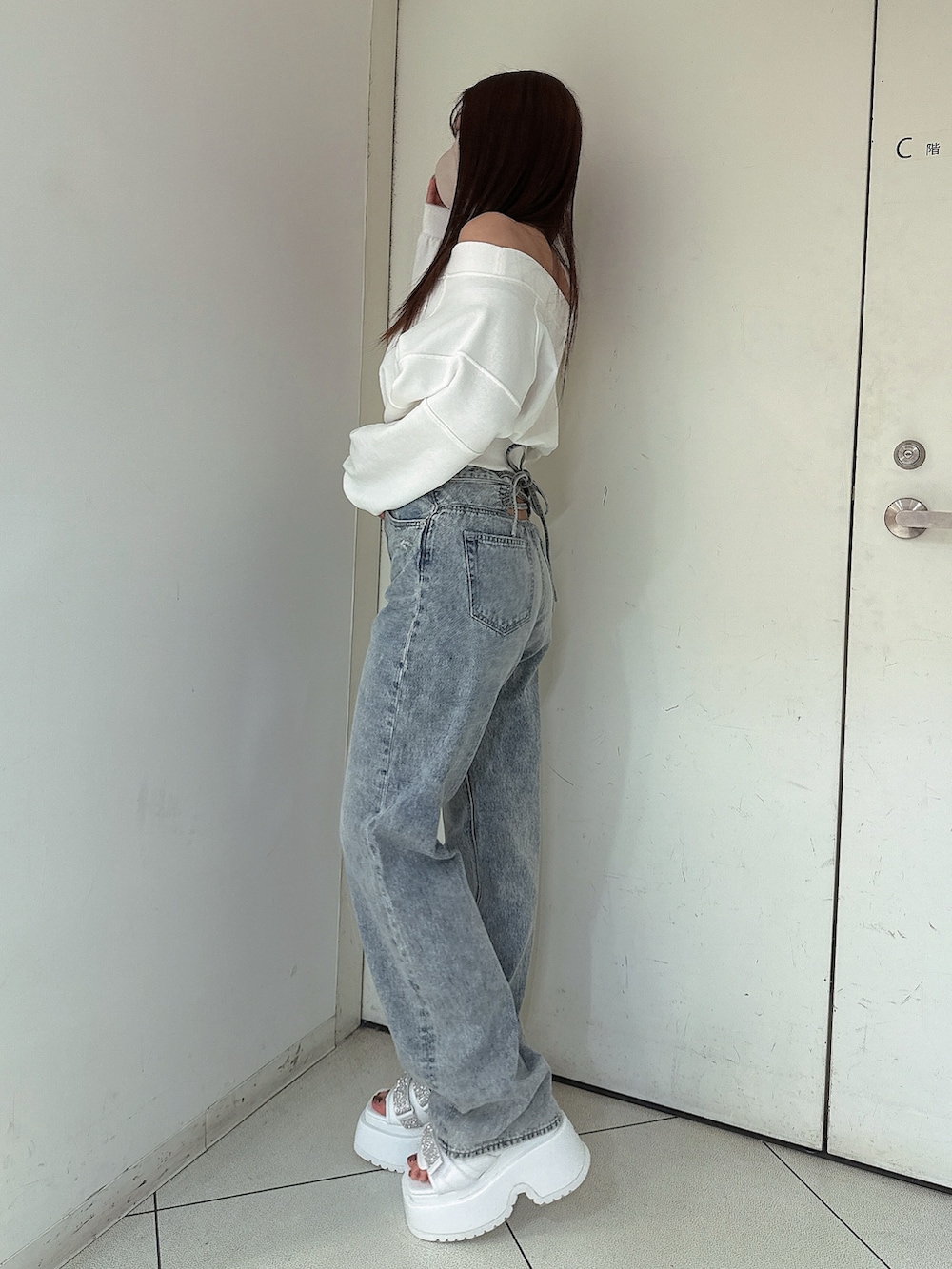 ホワイト系のスウェット、ブルー系のデニムパンツ、ホワイト系のサンダルを着用したレディースの冬コーディネートの2枚目の写真