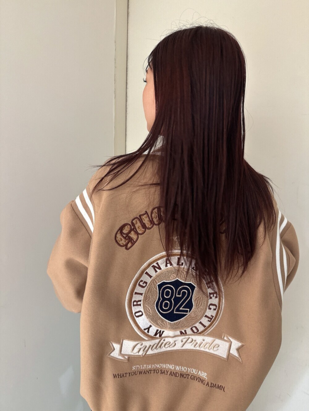 ブラック系のデニムパンツ、ブラック系のニット/セーター、ベージュ系のスタジャンを着用したレディースの秋コーディネートの6枚目の写真