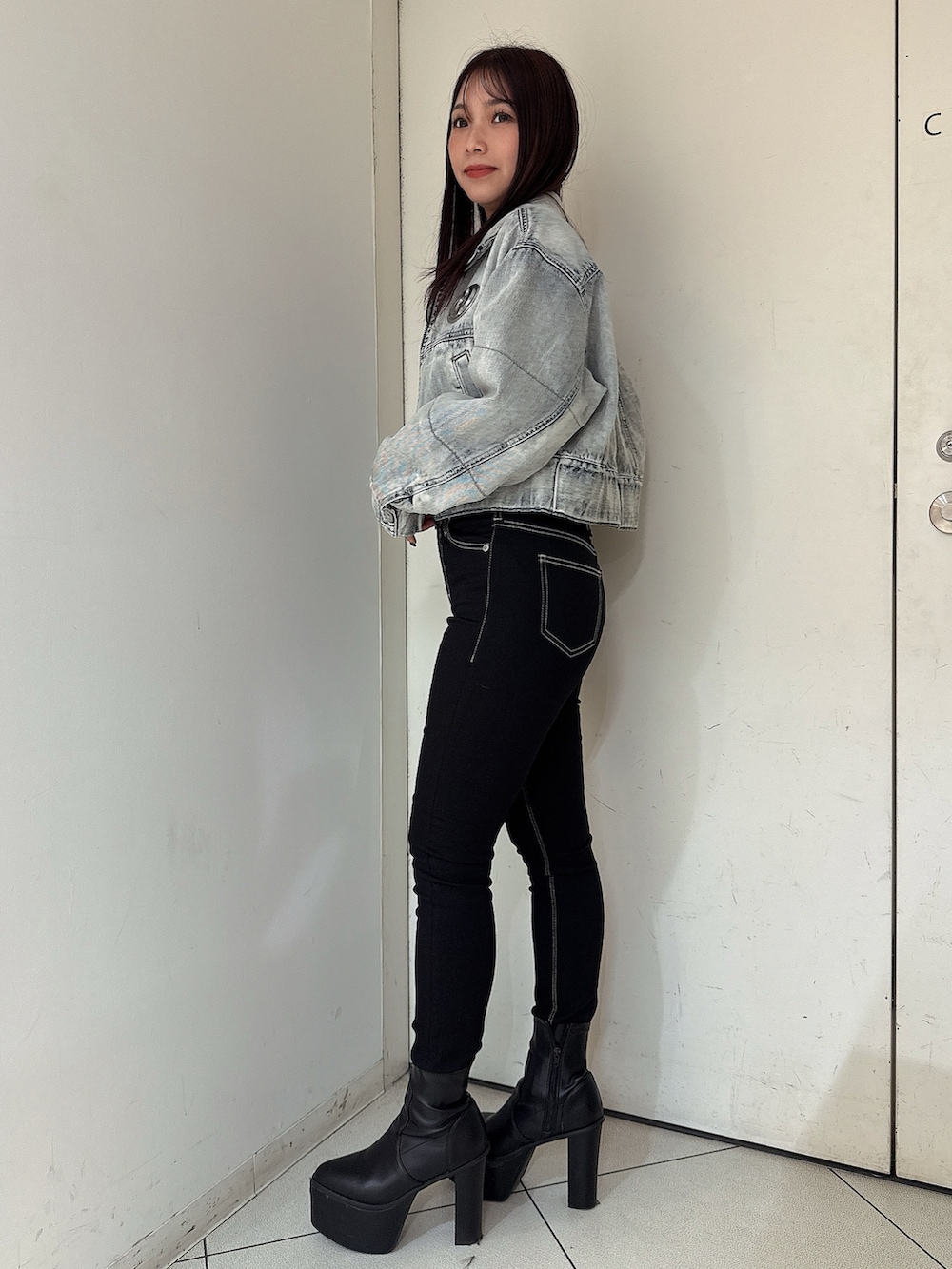 ブラック系のニット/セーター、ブラック系のデニムパンツ、ブラック系のブーツを着用したレディースの秋コーディネートの2枚目の写真