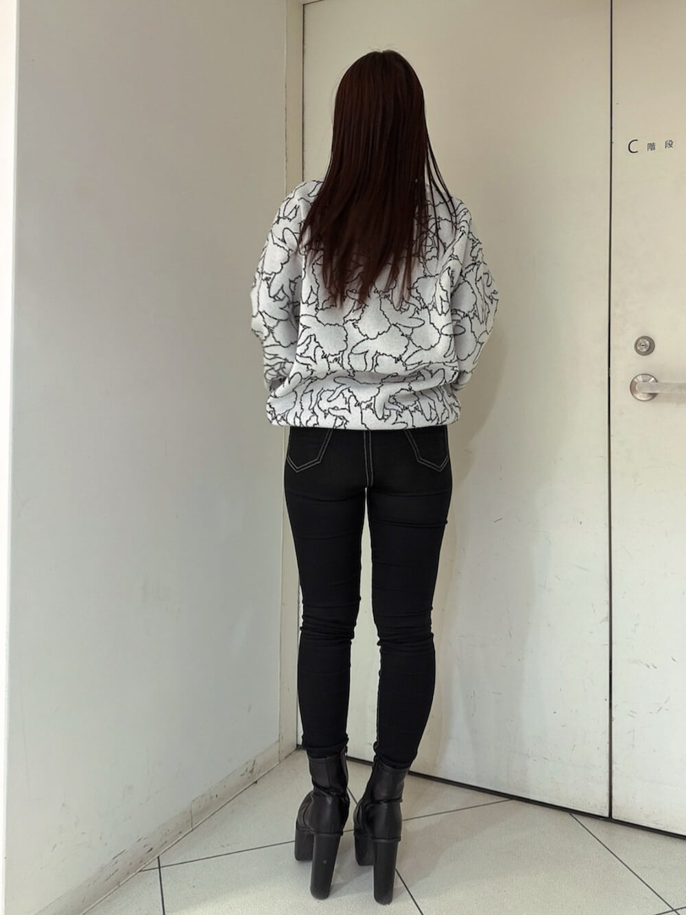 ブラック系のデニムパンツ、ブラック系のブーツ、ホワイト系のニット/セーターを着用したレディースの冬コーディネートの3枚目の写真