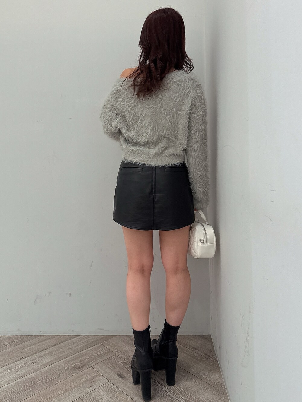 ブラック系のブーツ、ブラック系のスカート、ホワイト系のハンドバッグを着用したレディースの冬コーディネートの3枚目の写真