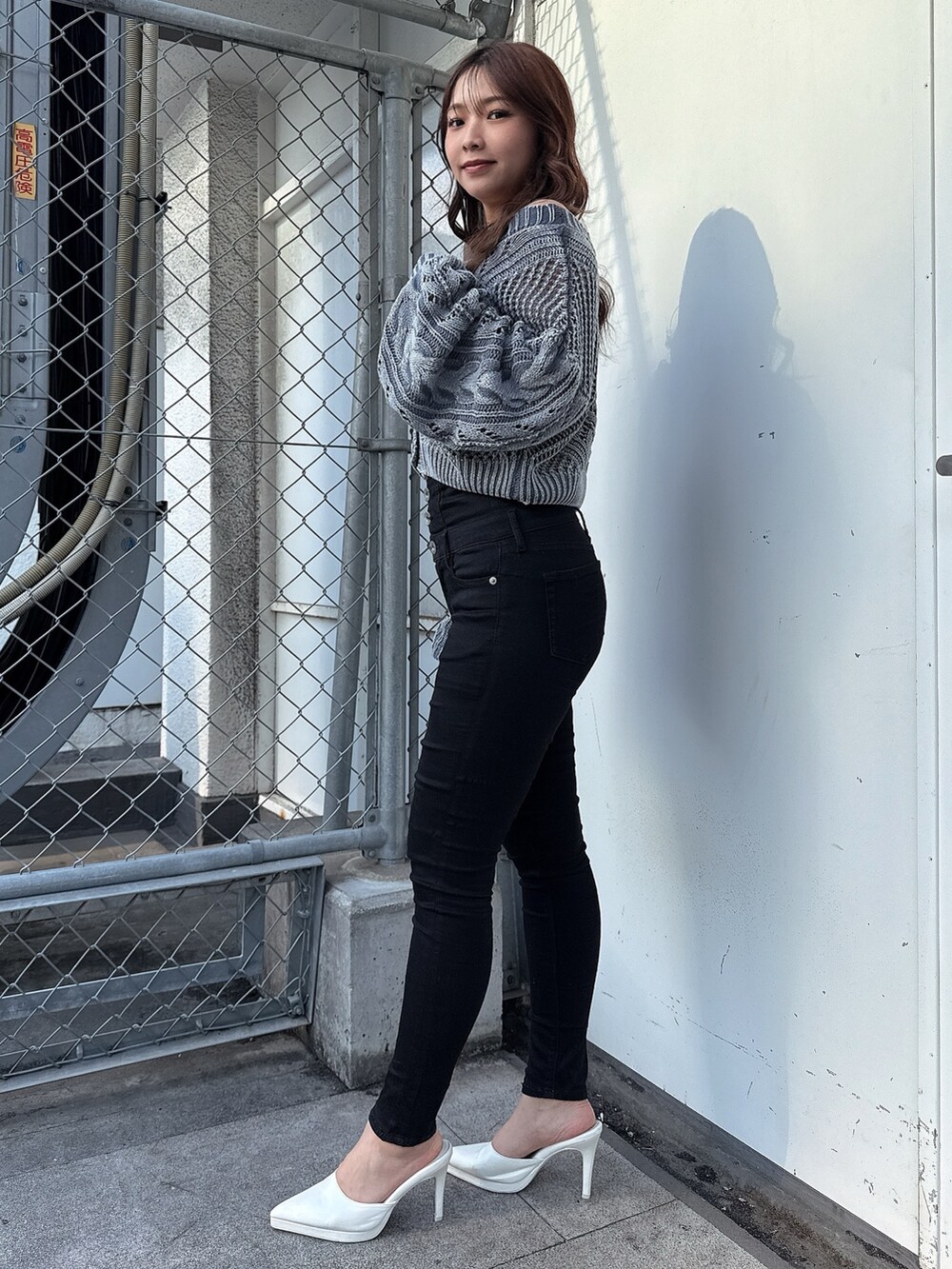 ブルー系のニット/セーター、ブラック系のデニムパンツ、ホワイト系のパンプスを着用したレディースの春コーディネートの2枚目の写真