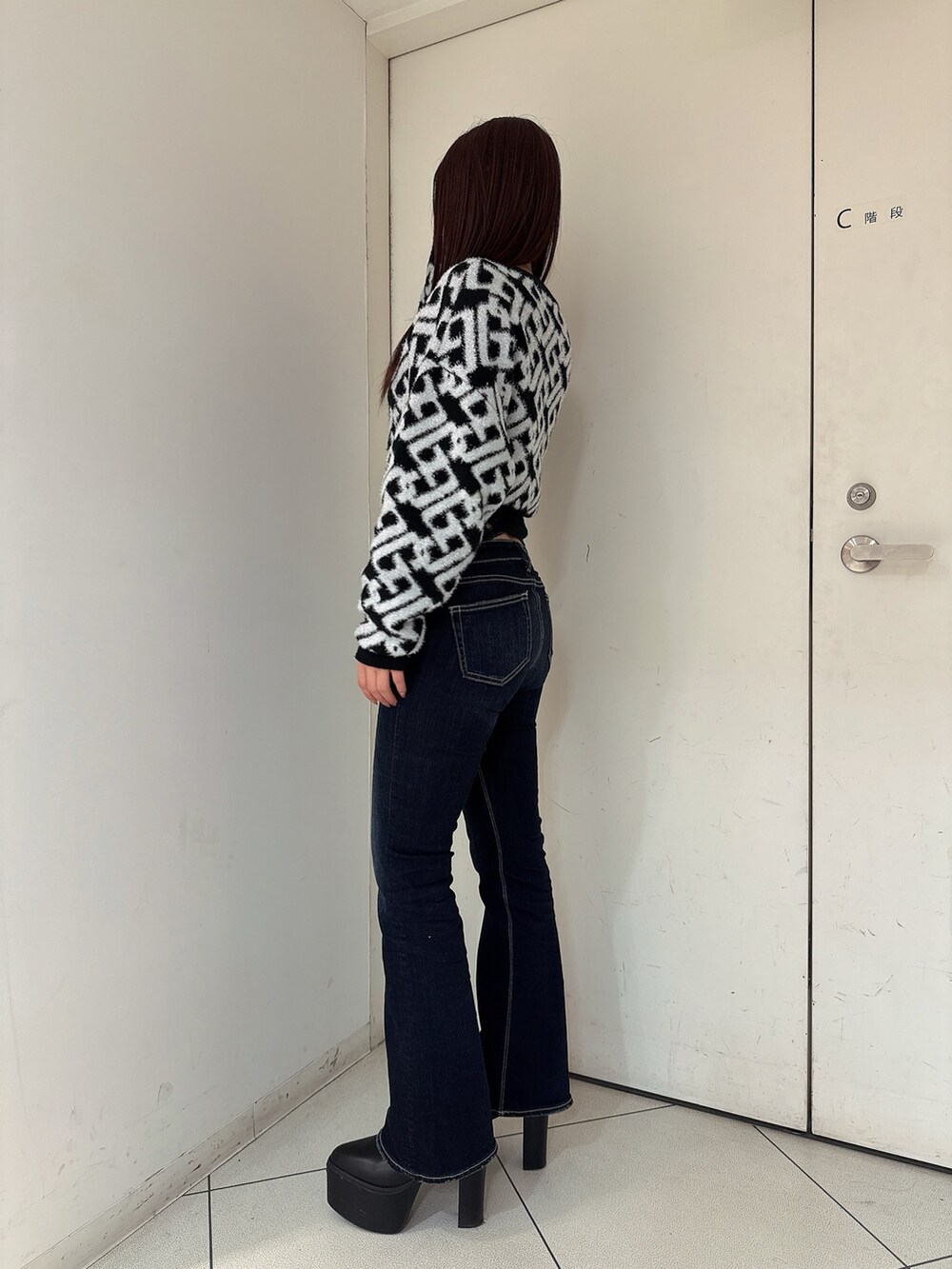 ブルー系のデニムパンツ、ブラック系のブーツ、ブラック系のニット/セーターを着用したレディースの秋コーディネートの2枚目の写真