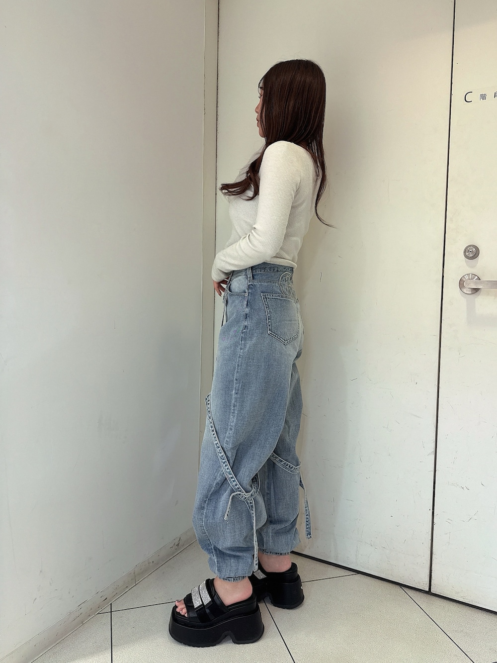 ブルー系のデニムパンツ、ブラック系のサンダル、ホワイト系のTシャツ/カットソーを着用したレディースの春コーディネートの2枚目の写真