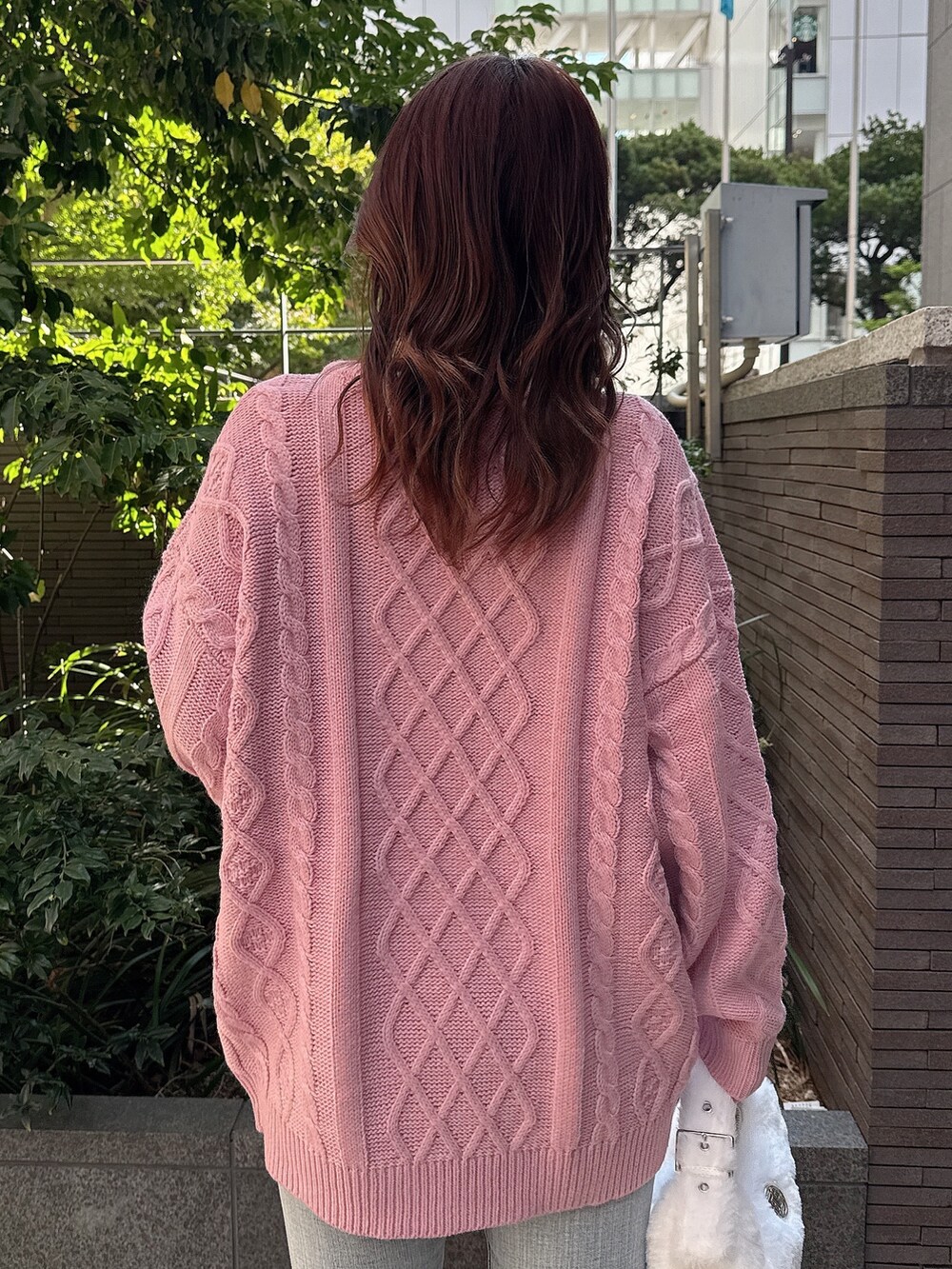 ピンク系のニット/セーター、ホワイト系のハンドバッグ、ブルー系のデニムパンツを着用したレディースの秋コーディネートの6枚目の写真