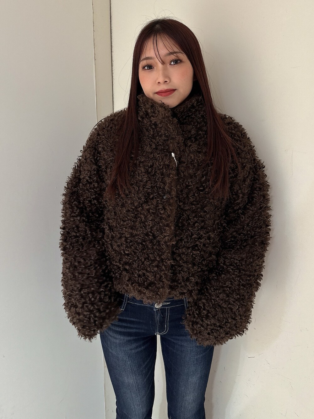 ブルー系のデニムパンツ、ブラック系のブーツ、ブラウン系のブルゾンを着用したレディースの秋コーディネートの4枚目の写真
