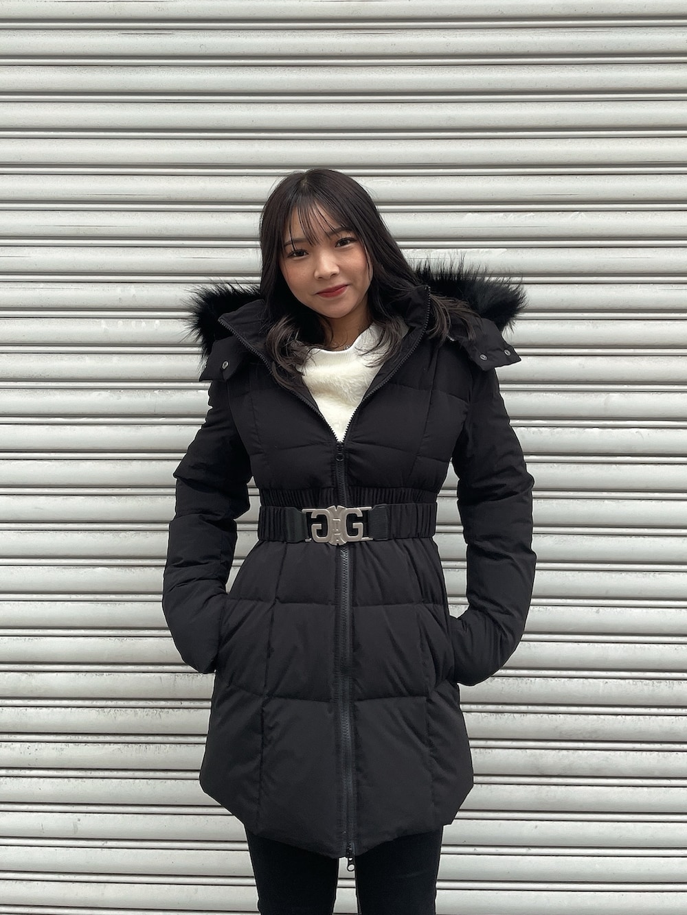 ブラック系のダウンジャケット/コート、ホワイト系のニット/セーター、ブラック系のデニムパンツを着用したレディースの冬コーディネートの4枚目の写真