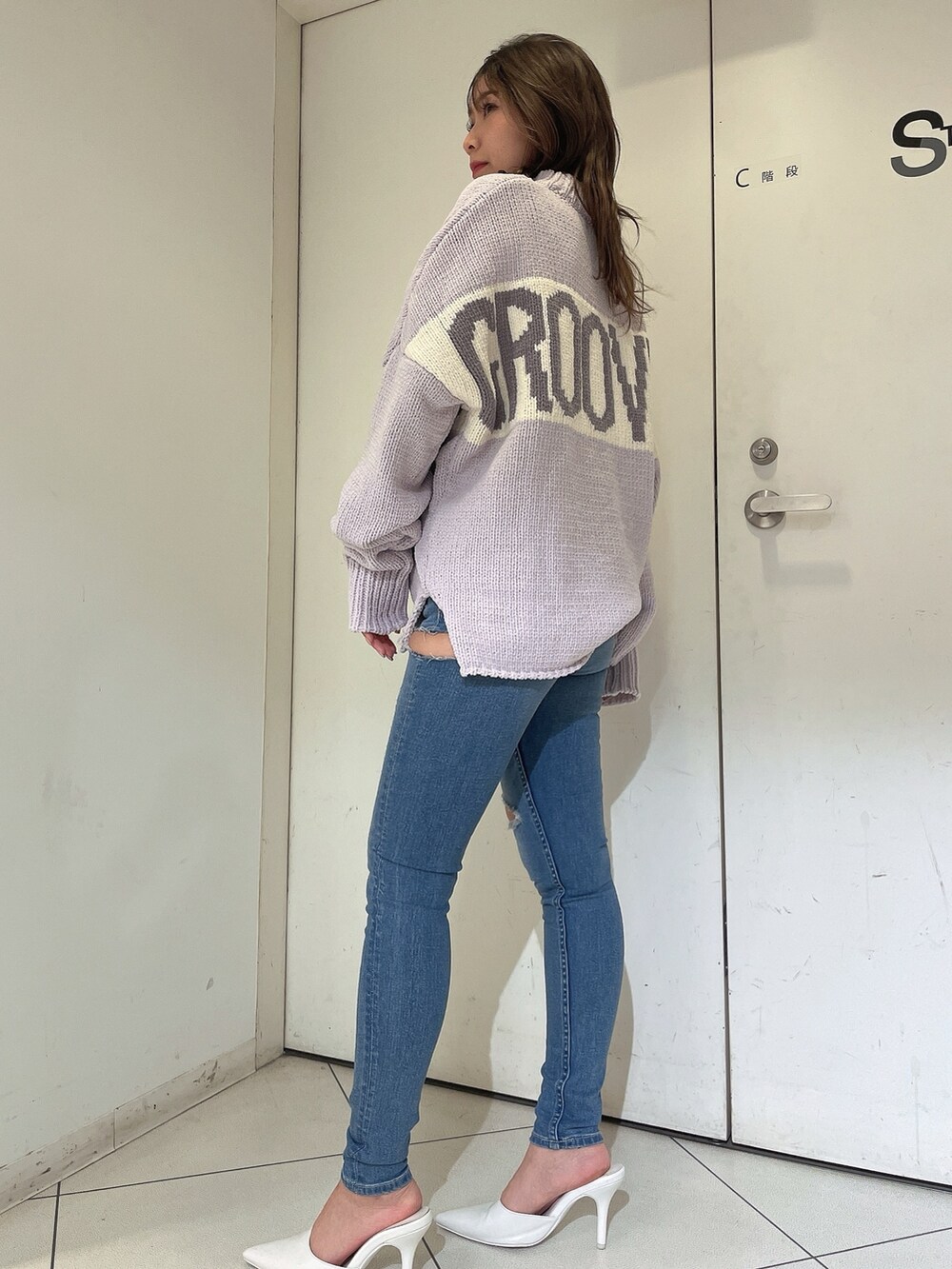 パープル系のニット/セーター、ブルー系のデニムパンツ、ホワイト系のパンプスを着用したレディースの冬コーディネートの2枚目の写真
