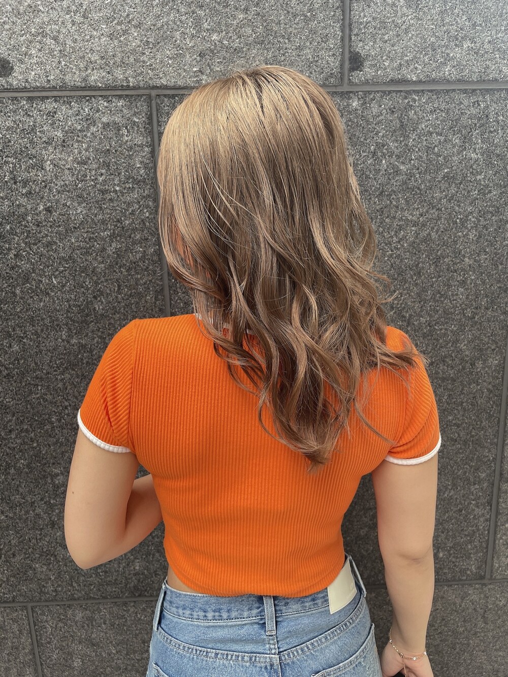 オレンジ系のTシャツ/カットソー、ブルー系のデニムパンツ、ブラック系のチューブトップを着用したレディースの夏コーディネートの4枚目の写真