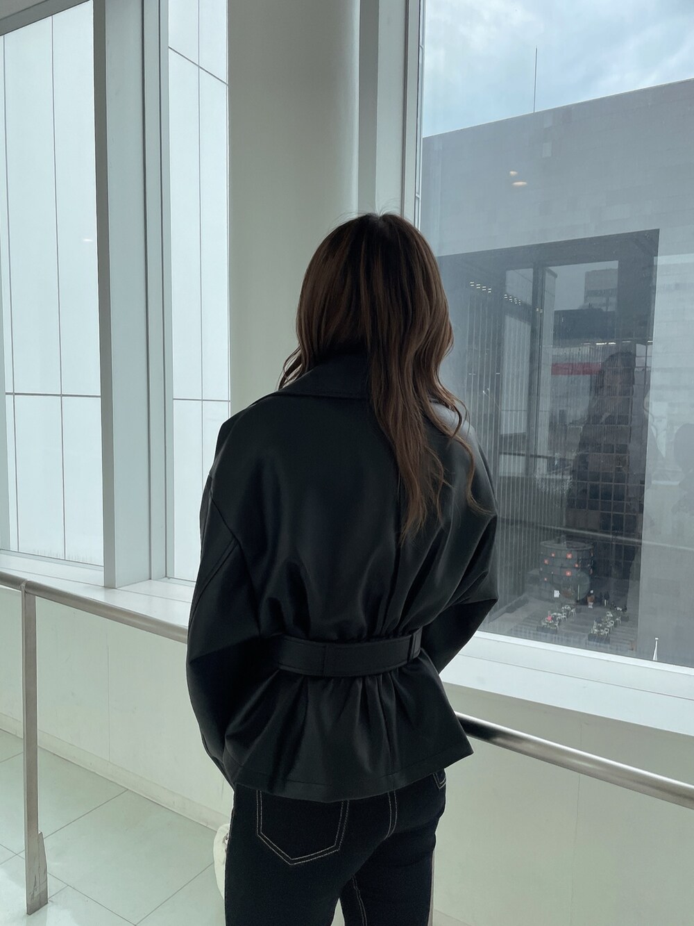 ブラック系のライダースジャケット、ブラック系のデニムパンツ、ホワイト系のハンドバッグを着用したレディースの冬コーディネートの4枚目の写真