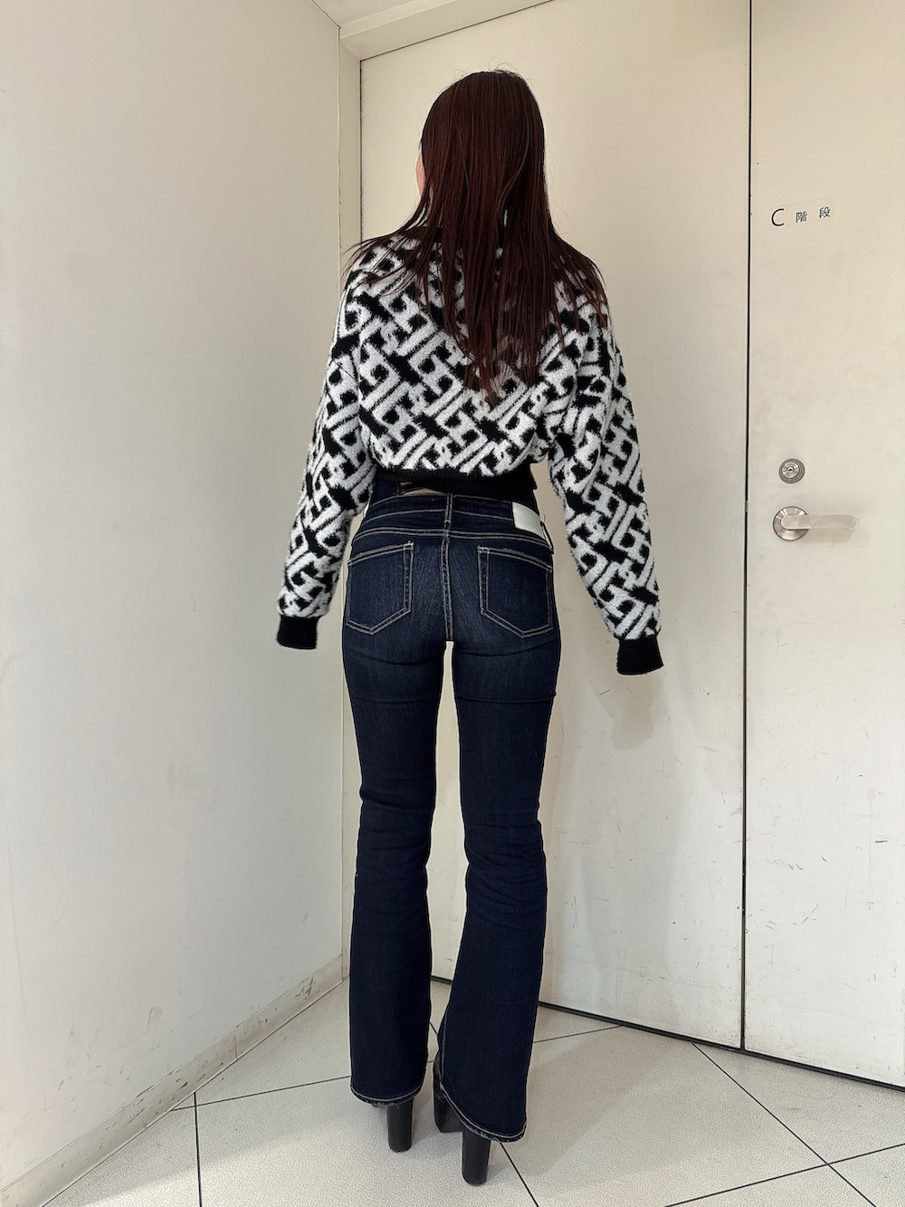 ブルー系のデニムパンツ、ブラック系のブーツ、ブラック系のニット/セーターを着用したレディースの秋コーディネートの3枚目の写真