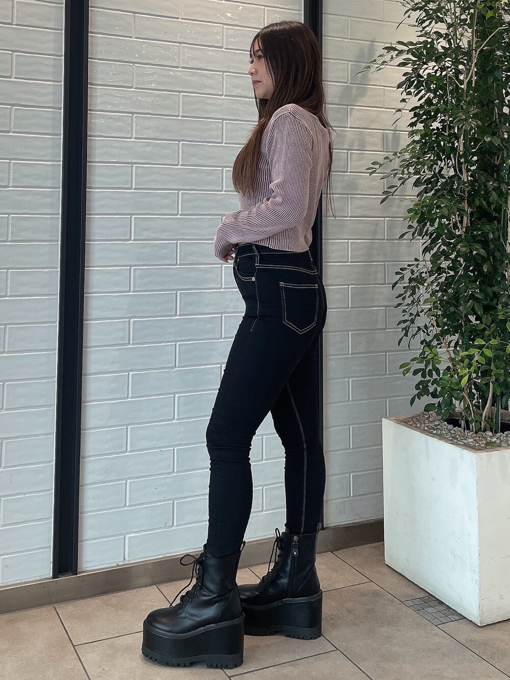 ピンク系のニット/セーター、ブラック系のデニムパンツ、ブラック系のブーツを着用したレディースの秋コーディネートの2枚目の写真