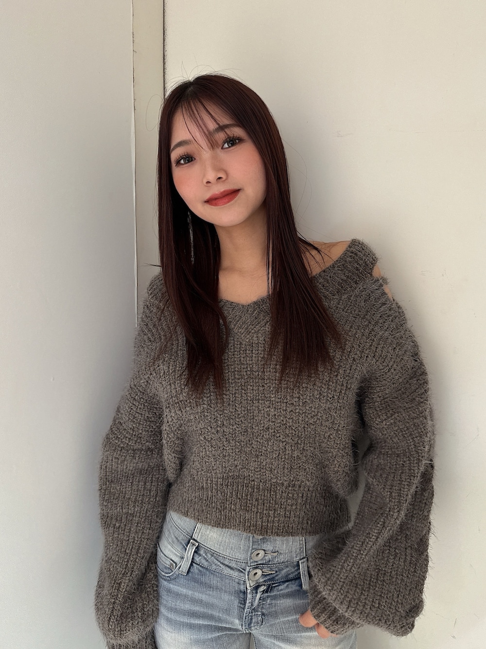 グレー系のニット/セーター、ブルー系のデニムパンツ、ブラック系のブーツを着用したレディースの秋コーディネートの4枚目の写真