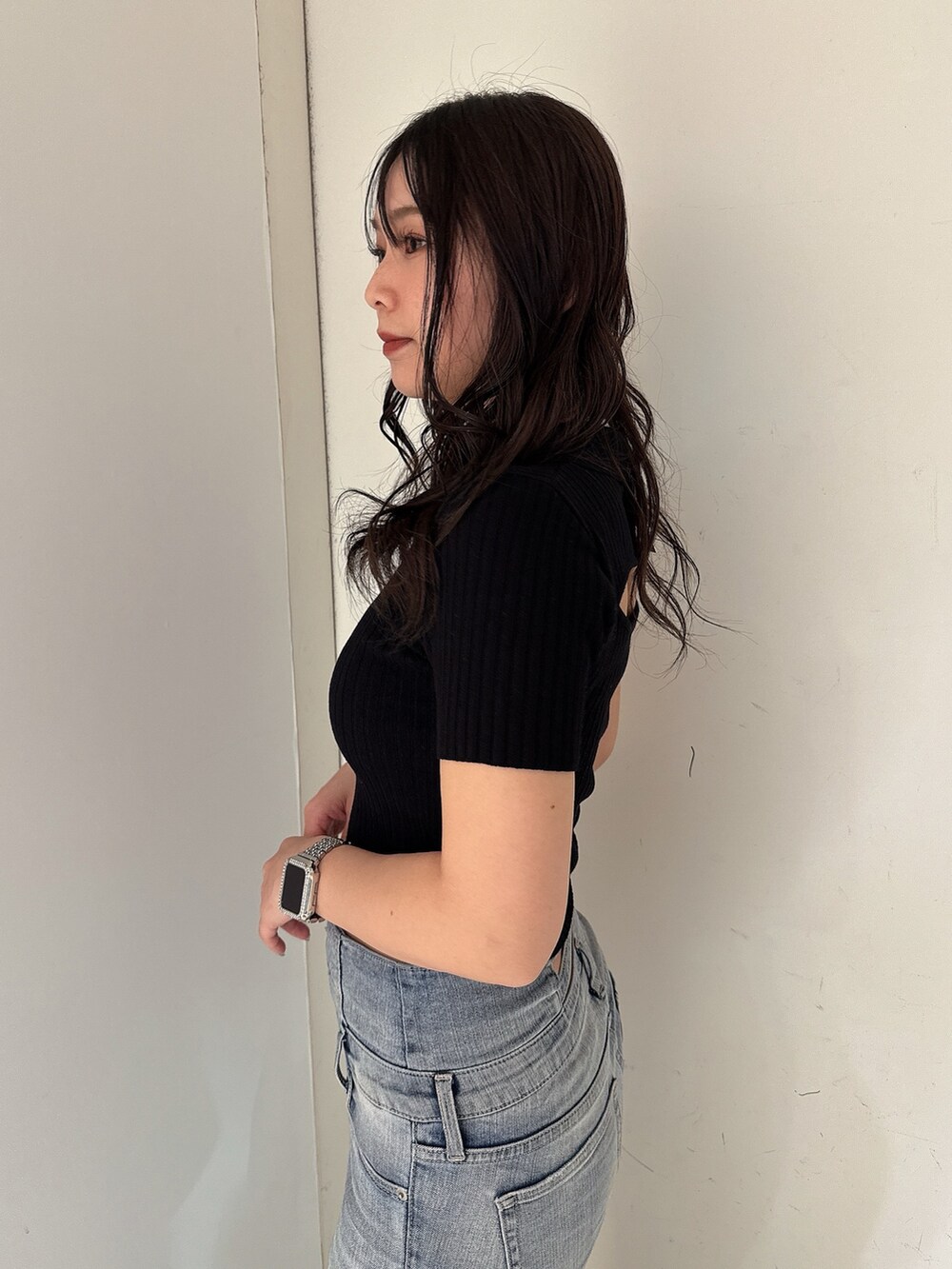 ブルー系のデニムパンツ、ブラック系のニット/セーター、ホワイト系のサンダルを着用したレディースの春コーディネートの5枚目の写真