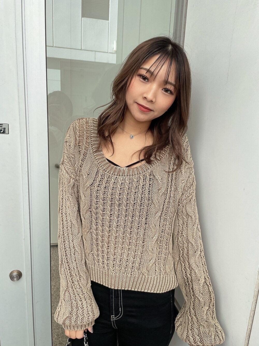 ベージュ系のニット/セーター、ブラック系のキャミソール、ブラック系のデニムパンツを着用したレディースの冬コーディネートの5枚目の写真